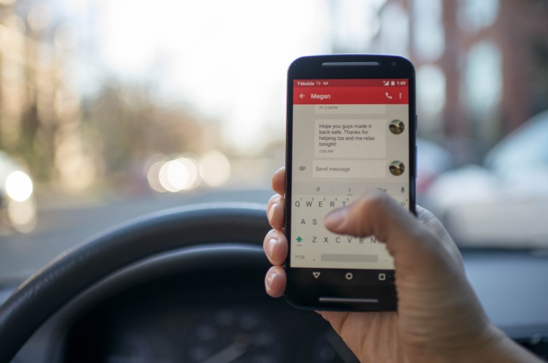 man sending a text while driving a car